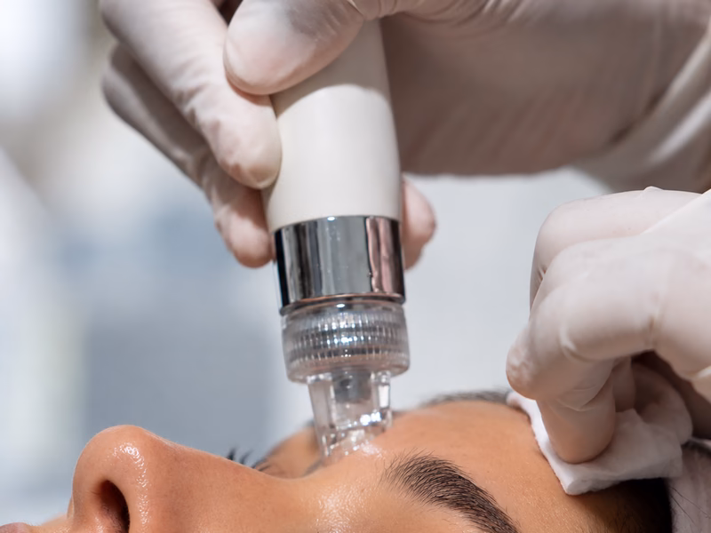 A HydroGlow facial handpiece being used on a client’s forehead